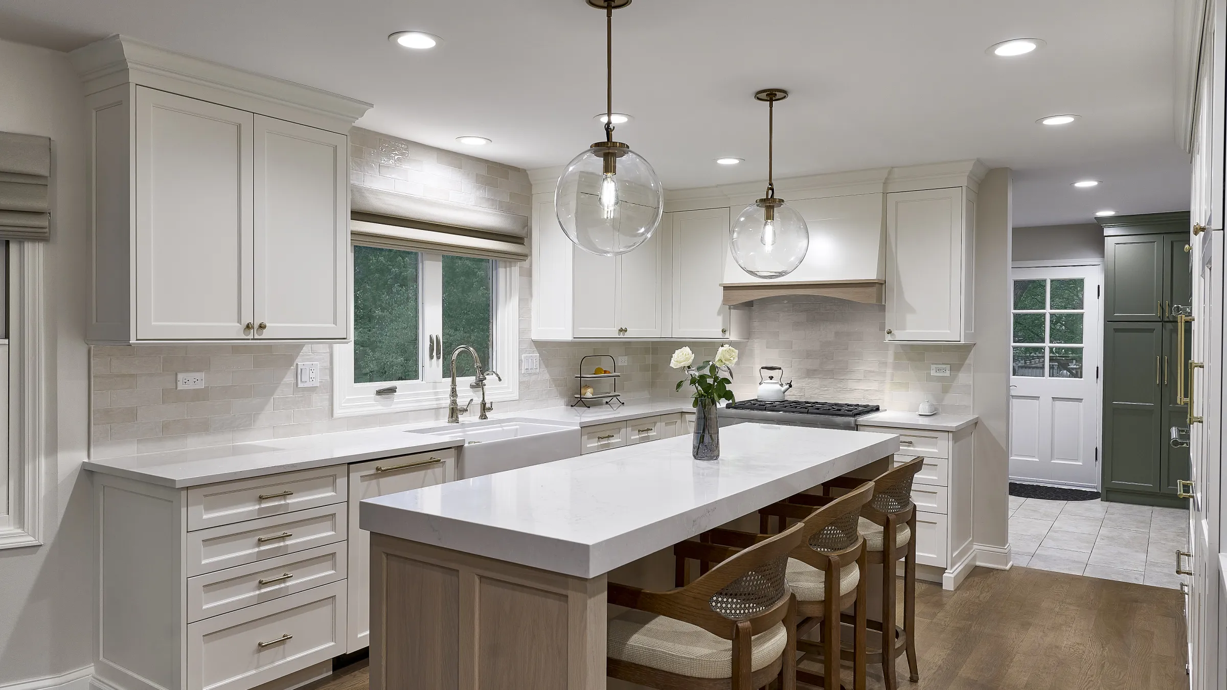 Modern white kitchen with shaker cabinets, quartz countertops, wood island, farmhouse sink, pendant lights, and wood flooring