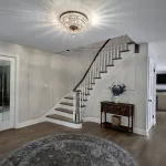 Elegant foyer with dark hardwood floors, a curved staircase with white risers and dark treads, and a crystal chandelier.