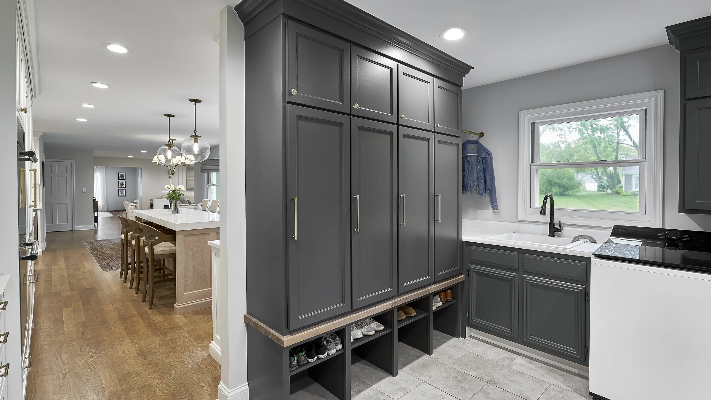 Modern open-concept first floor remodel featuring a laundry room with dark gray shaker cabinets, utility sink, washer, and mu