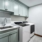Modern laundry room with mint green shaker cabinets, white quartz countertop, stainless sink, patterned backsplash, and LG wa