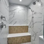 Modern primary bathroom shower with white marble-look tiles, chrome fixtures, and a wood-look hexagonal tile accent niche.