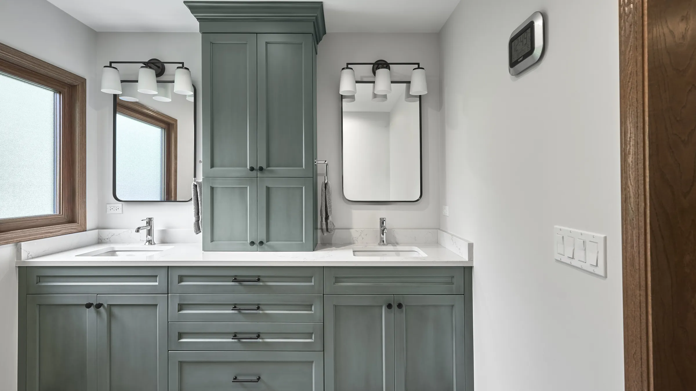 Modern primary bathroom with sage green shaker cabinets, white quartz countertops, dual sinks, black mirrors, and chrome fixt