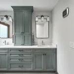 Modern primary bathroom with sage green shaker cabinets, white quartz countertops, dual sinks, black mirrors, and chrome fixt