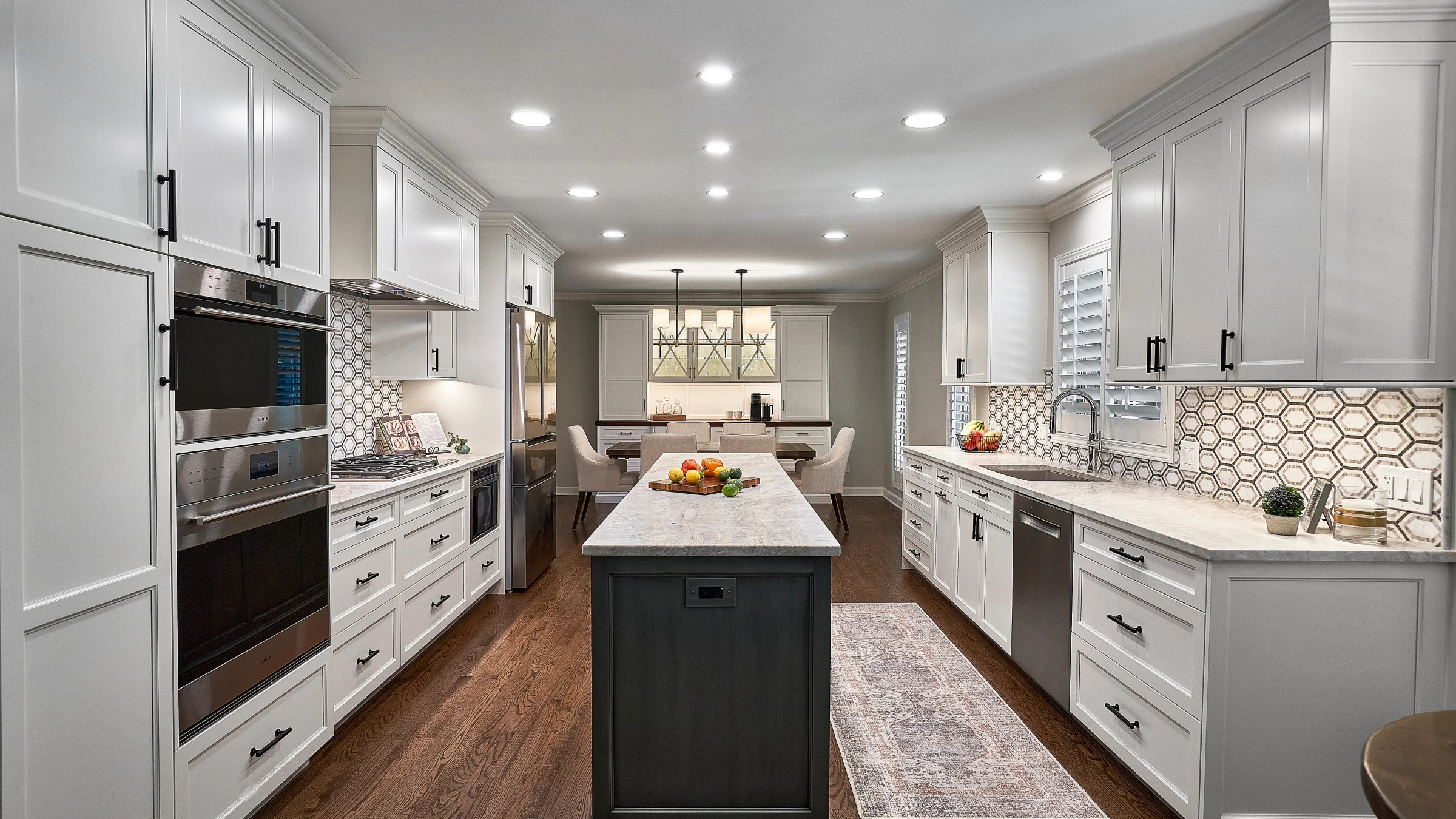 Bright kitchen remodel with white cabinets, dark island, marble countertops, and hardwood floors in Palatine, IL.