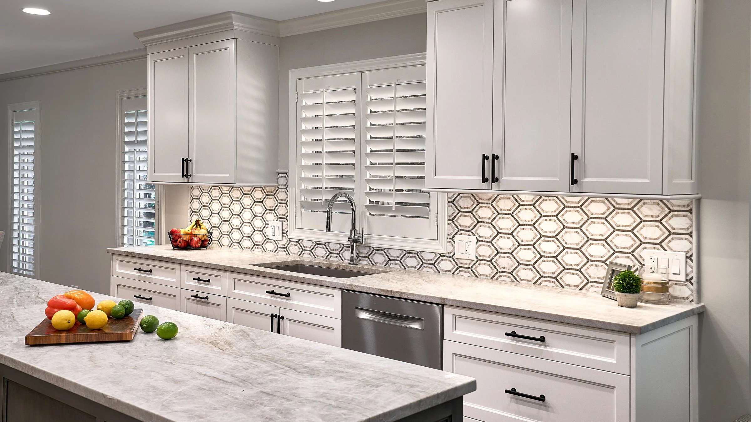 Palatine, IL kitchen remodel featuring white cabinets, marble countertops, mosaic backsplash, and stainless steel appliances.