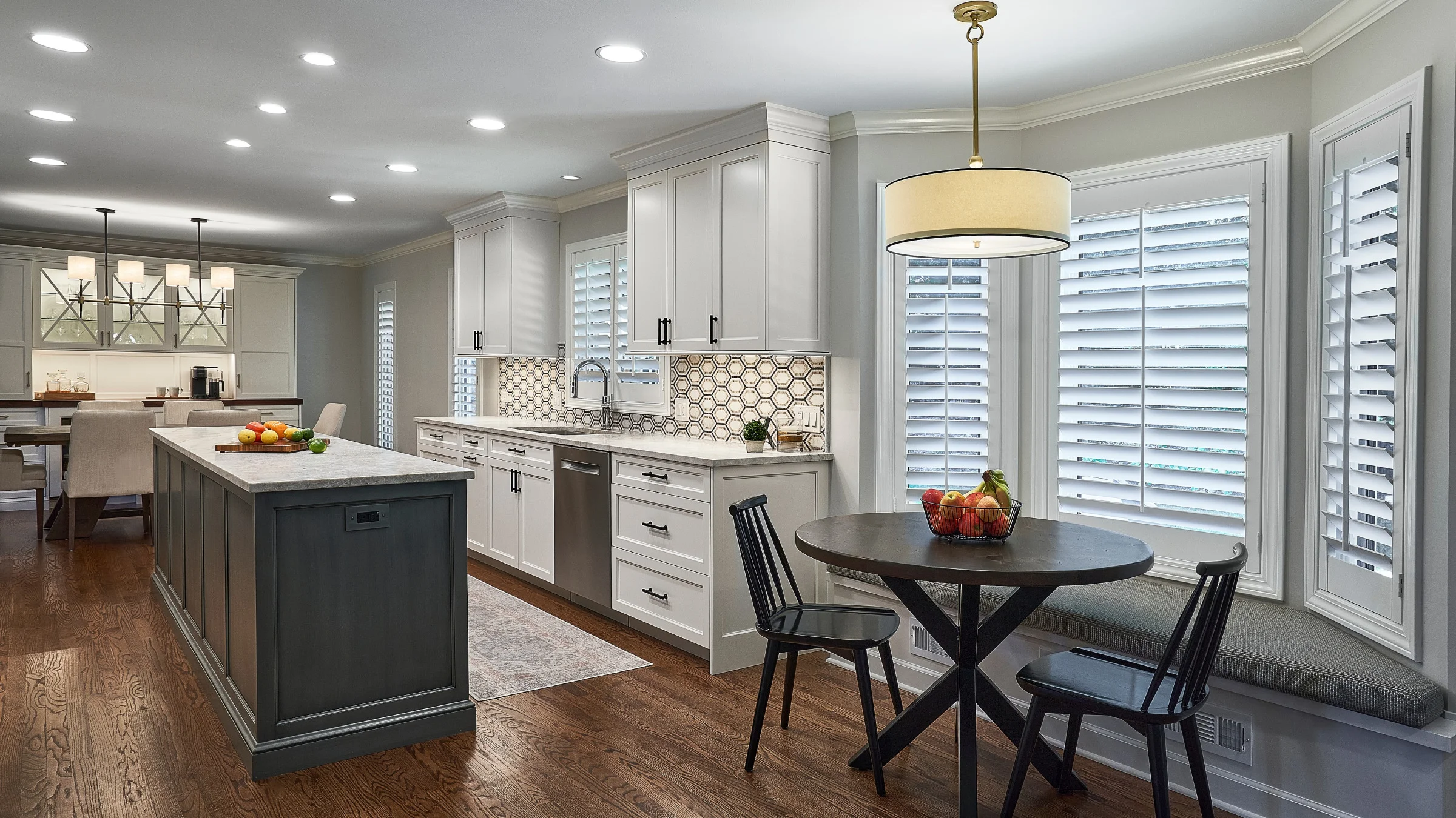 Bright kitchen remodel with white cabinets, dark island, wood floors, and breakfast nook in Palatine, IL.