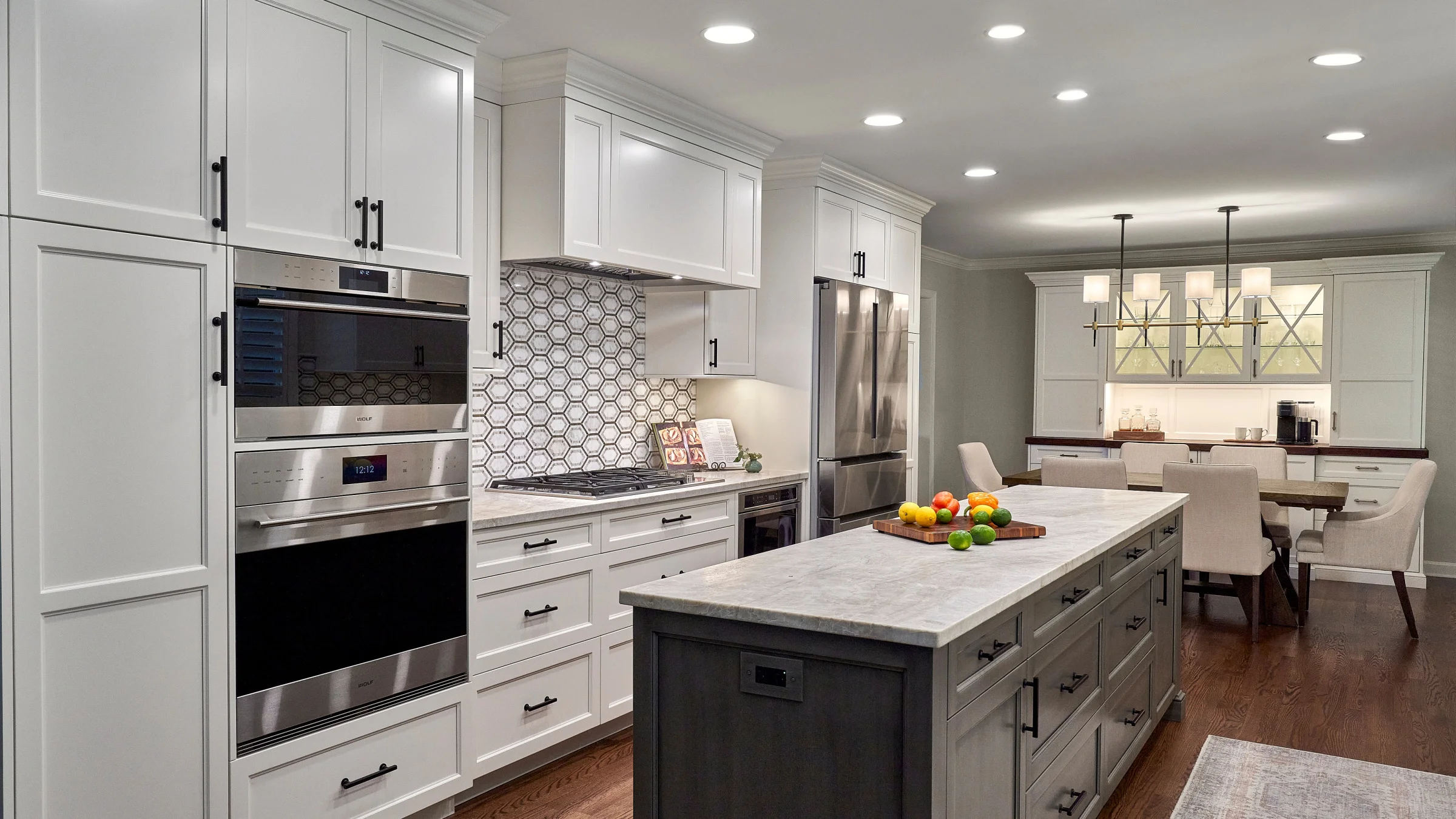 Palatine, IL Kitchen Remodel: White cabinets, gray island, stainless steel appliances, hardwood floors, and modern lighting.