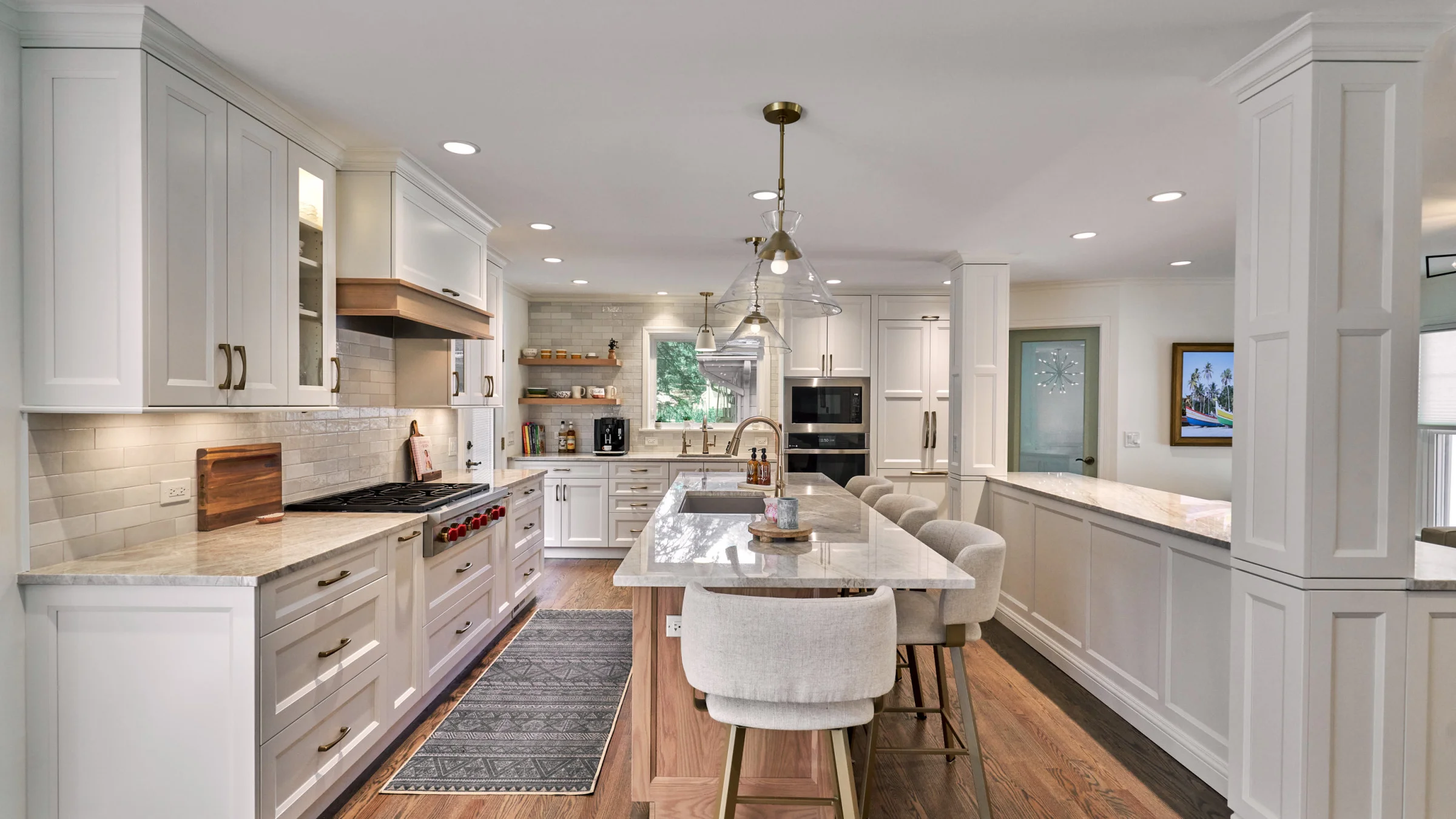 Bright kitchen remodel with white cabinets, marble countertops, wood floors, island seating, and pendant lighting. Arlington 