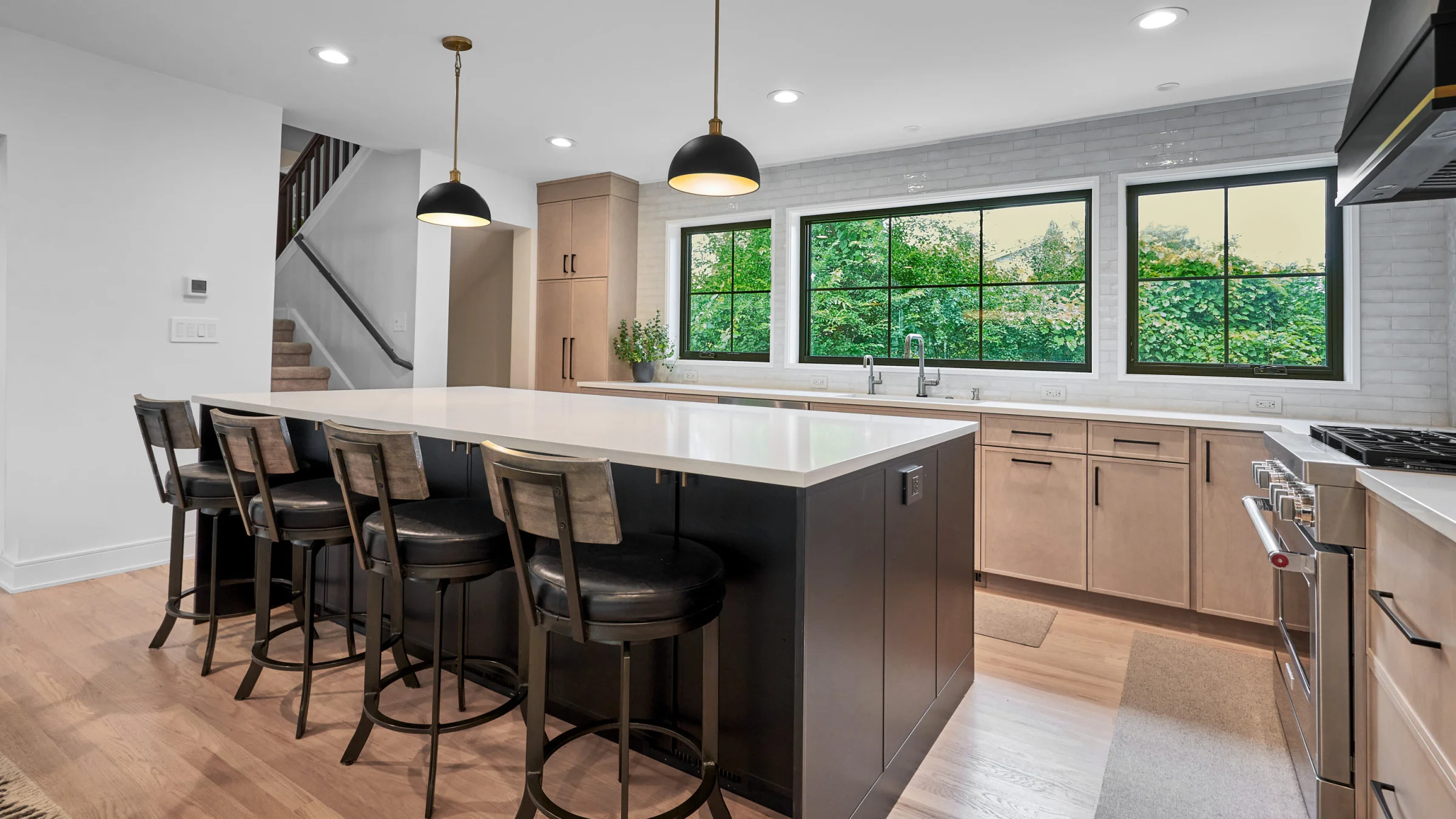 Modern Palatine kitchen remodel featuring large island, quartz countertop, wood cabinets, black pendant lights, hardwood floo