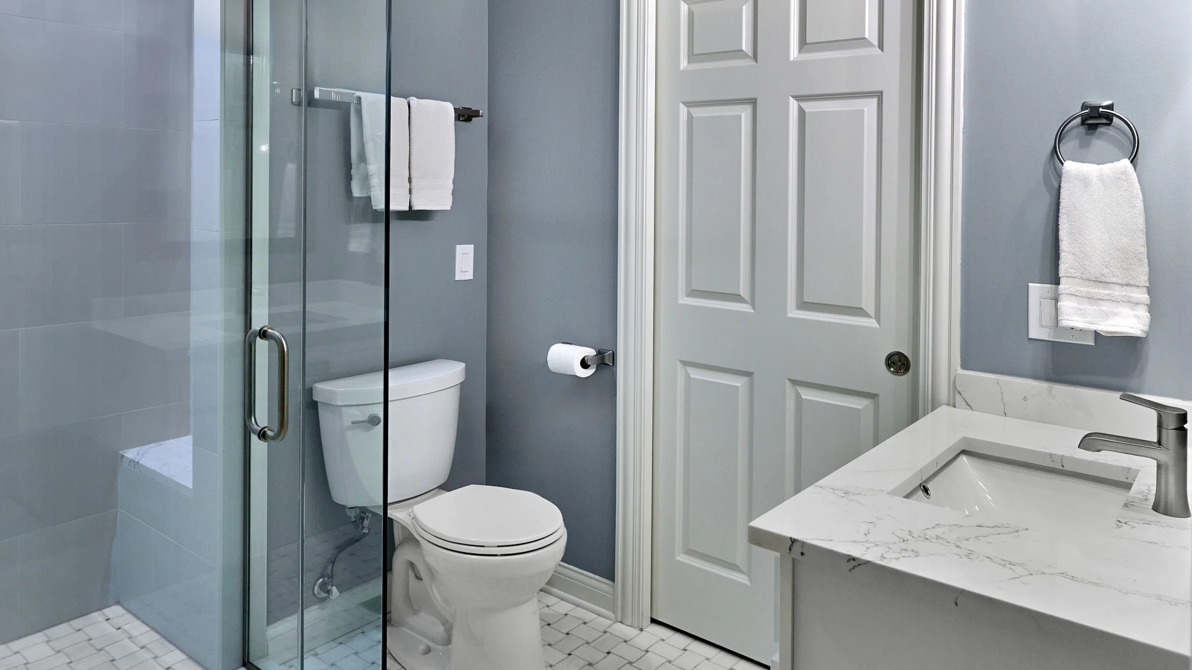 Arlington Heights bathroom remodel featuring a glass shower, white toilet, marble countertop vanity, and gray walls.