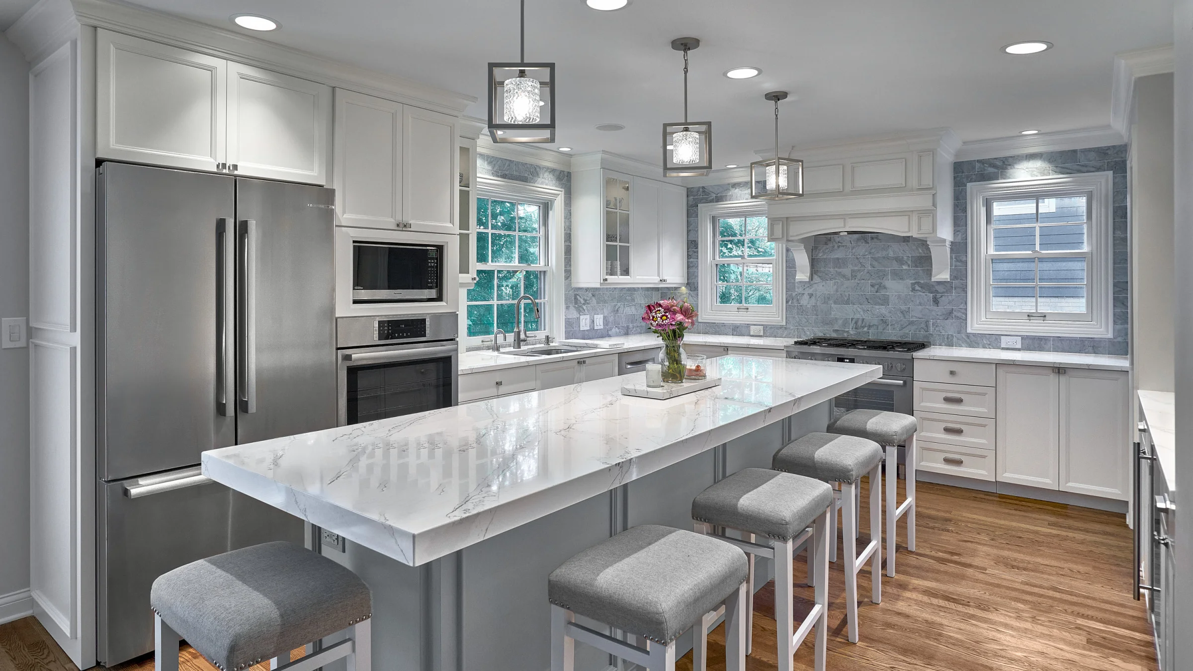 Bright, modern kitchen remodel in Arlington Heights featuring white cabinets, marble countertops, island seating, and pendant