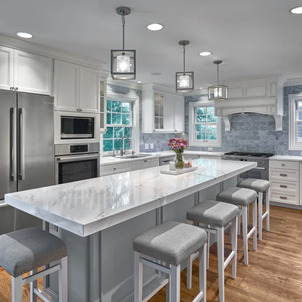 Bright, modern kitchen remodel in Arlington Heights featuring white cabinets, marble countertops, island seating, and pendant