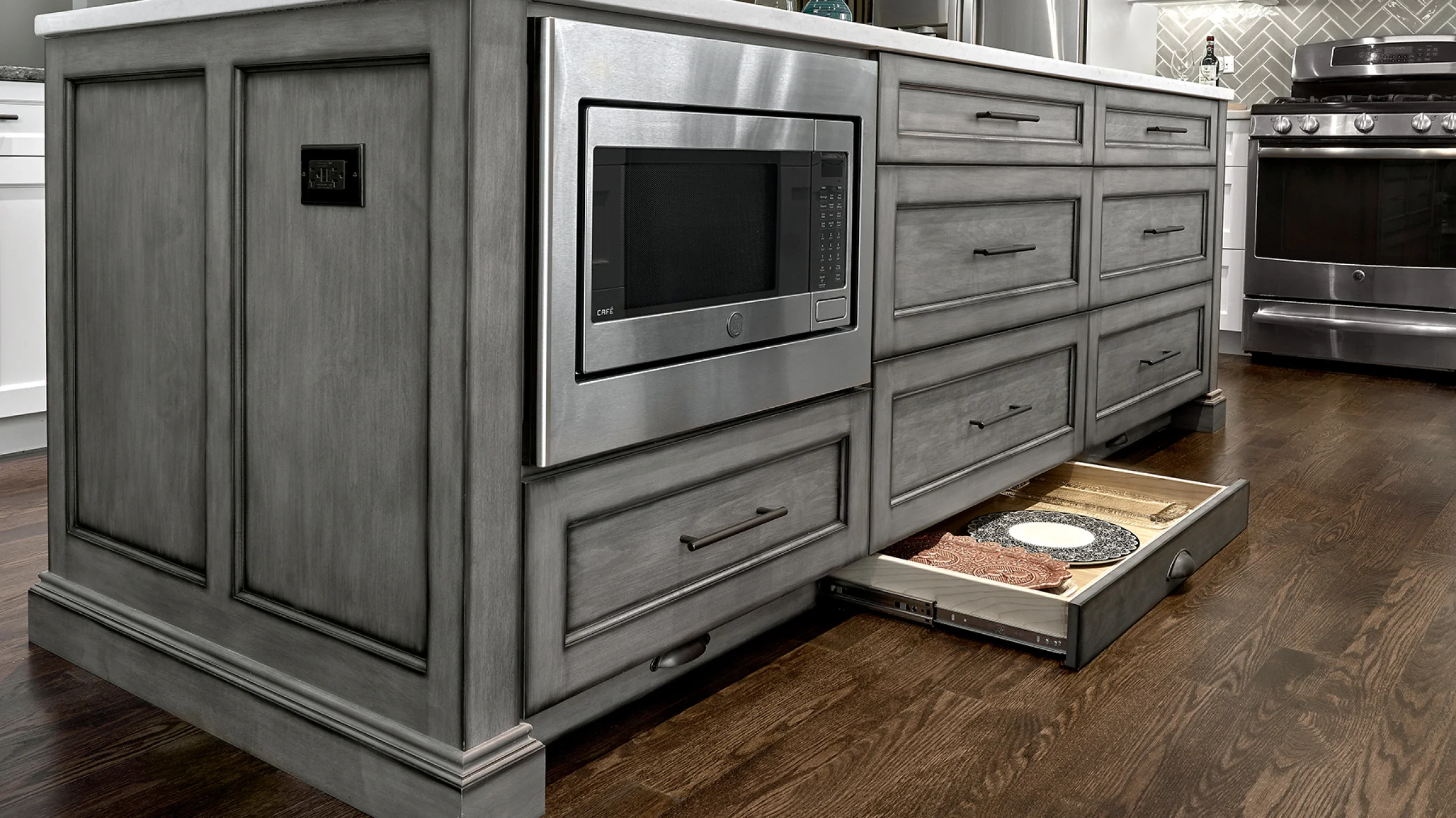 Hoffman Estates kitchen remodel: Grey custom cabinets, microwave, and hardwood floors. Open drawer with dishes.