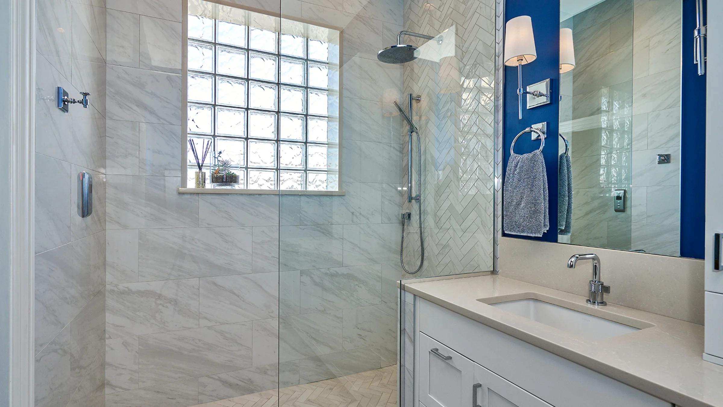 Chicago bathroom remodel with glass shower, marble tile, white vanity, and blue accent wall.