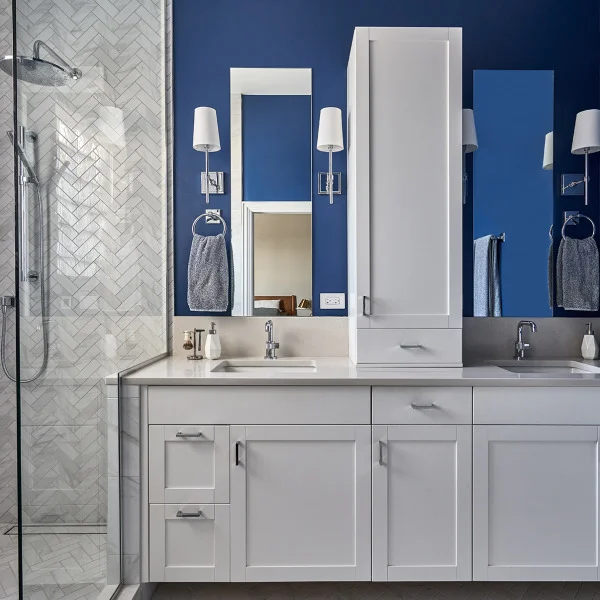 Chicago bathroom remodel: double vanity with white cabinets, blue walls, herringbone tile shower, modern lighting.